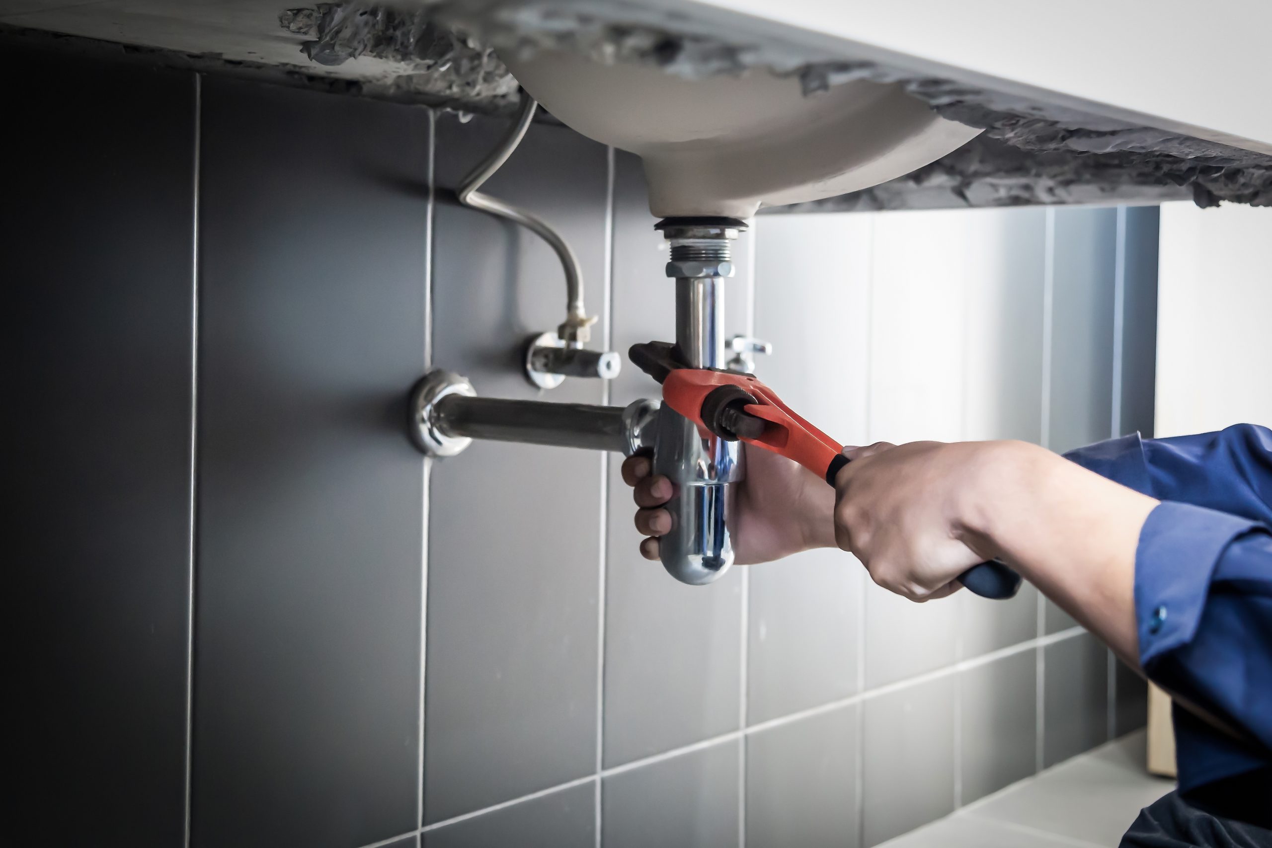 Plumber uses wrench to repair water pipe